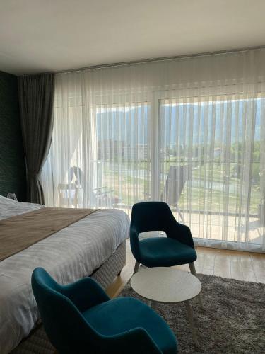 a hotel room with a bed and a chair and a window at Your River Walk - Ilidza in Sarajevo