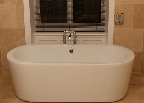 a white bath tub in a bathroom with a window at Maes Manor Country Hotel in Blackwood