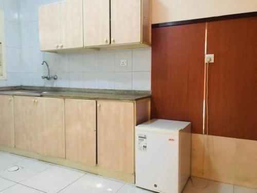 a kitchen with wooden cabinets and a refrigerator at Lulu guest house in Ras al Khaimah