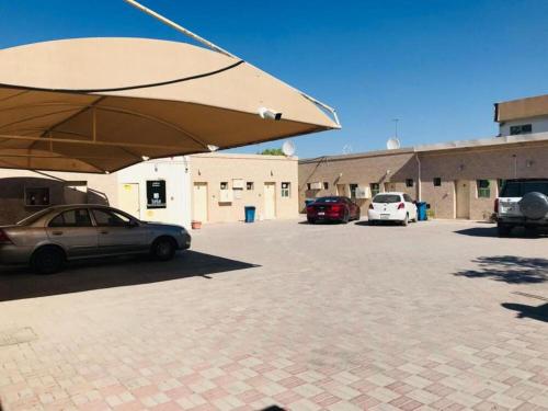 a car parked in a parking lot with a large umbrella at Lulu guest house in Ras al Khaimah