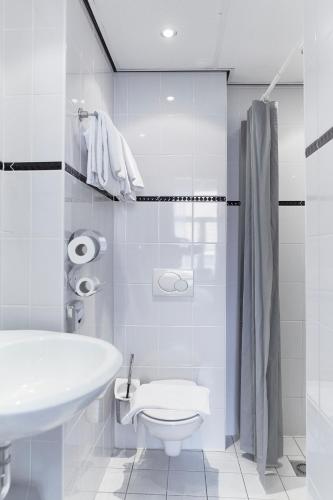 a white bathroom with a toilet and a sink at Hotel de la Bourse in Maastricht
