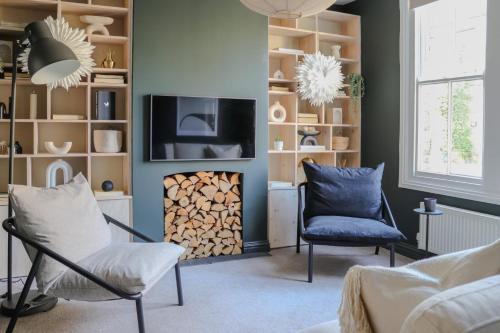 a living room with a fireplace and a tv and chairs at Beautiful Oxford Townhouse near City Centre in Oxford
