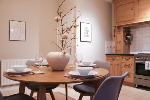 einem Esstisch mit Stühlen und einer Vase darauf in der Unterkunft Beautiful Oxford Townhouse near City Centre in Oxford