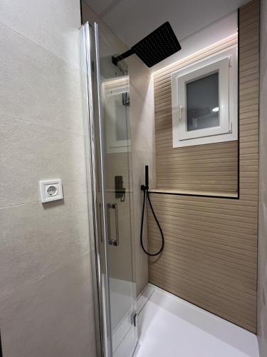 a bathroom with a shower and a television on the wall at Moratalaz Apartments in Madrid