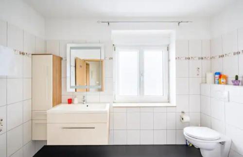 een witte badkamer met een wastafel en een toilet bij Preiswertes stilvolles Zimmer im privaten Haus mit großem schönem modernem Gemeinschaft Badenzimmer in Lörrach