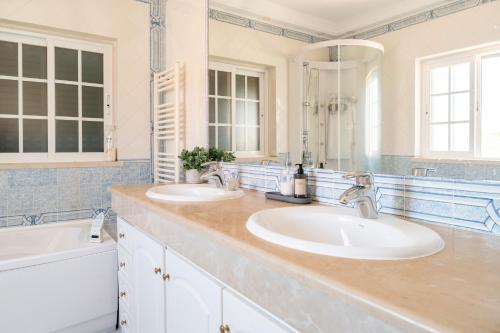 La salle de bains est pourvue de 2 lavabos et d'un grand miroir. dans l'établissement Villa Privée Prestige, à Cascais