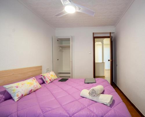 Una cama morada con dos toallas encima. en Casa Calera. Con terraza y bbq, en Santa Pola