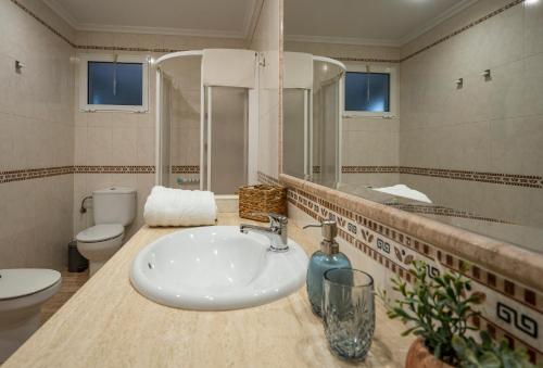 ein Badezimmer mit einem Waschbecken, einem WC und einem Spiegel in der Unterkunft Casa Calera. Con terraza y bbq in Santa Pola
