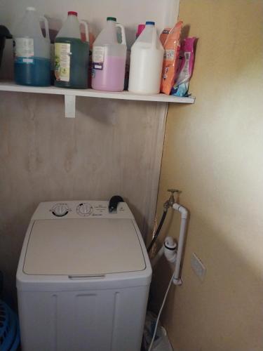 a bathroom with a toilet with milk bottles on a shelf at Monet's sweet Haven in Spanish Town