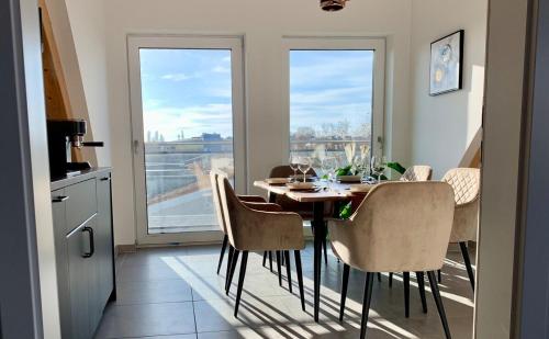 ein Esszimmer mit einem Tisch, Stühlen und Fenstern in der Unterkunft Luxury Penthouse Jacuzzi, Pool Table, Bbq & Desks in Berlin