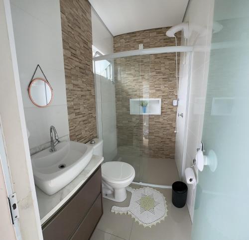 uma casa de banho branca com um lavatório e um WC em Residencial Marina em Florianópolis