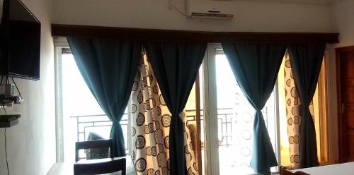 dwa okna z niebieskimi zasłonami w pokoju w obiekcie Annexe RAOOF HOTEL w mieście Mahajanga