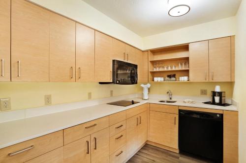 a kitchen with wooden cabinets and a black dishwasher at Staybridge Suites Columbia - Baltimore by IHG in Columbia