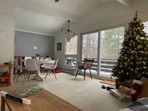 a living room with a christmas tree in it at Chalet dans les arbres. 3 ch. /trees house 3bdr in Lac Sainte-Marie