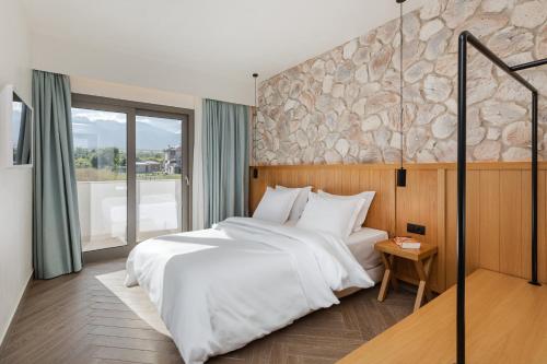 a bedroom with a white bed and a stone wall at White Nest Villas in Litochoro