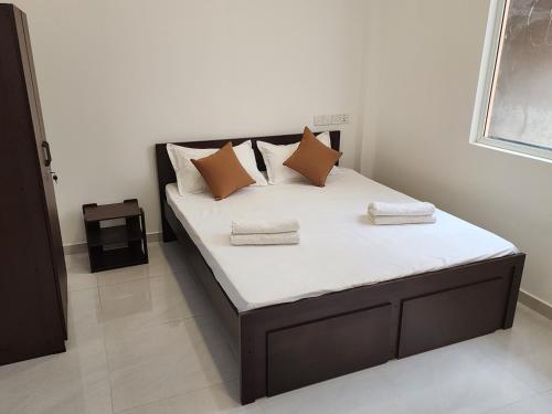 uma cama com almofadas castanhas num quarto em Joywin Apartments Airport transit em Negombo