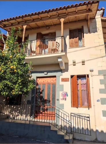 a house with a balcony and a tree at The house of ZORBAS in Agios Vlasios