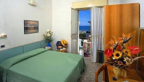 Hotel Bella Romagna في ريميني: غرفة نوم بسرير اخضر وإطلالة على المحيط