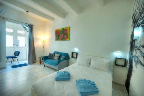 a bedroom with a white bed and a blue chair at Charming 3 storey apartment in Valletta centre, NGRI1-1 in Valletta