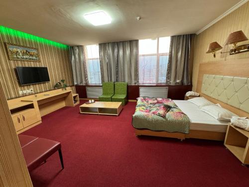 a hotel room with a bed and a tv at Zolotoi Drakon Hotel in Almaty