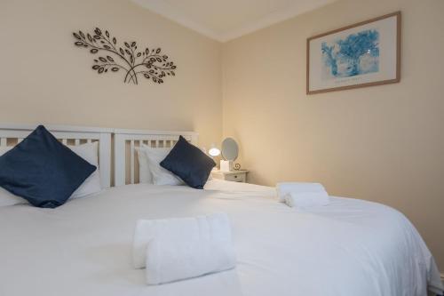 a bedroom with two white beds with blue pillows at Pretty Apartment in the Cathedral City of Ripon in Ripon