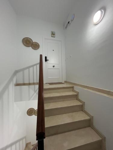 a hallway with a staircase with a white door and a white wall at APARTAMENTOS JUAN RAMÓN JIMÉNEZ 3 in Utrera
