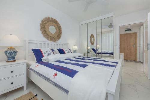 ein weißes Schlafzimmer mit einem Bett und einem Spiegel in der Unterkunft Apartament Ambra Marina - Basen & SPA in Dziwnów