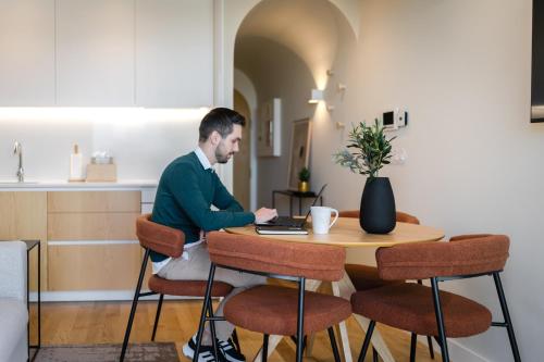 a man sitting at a table with a laptop at Feel Porto Corporate Housing Boavista in Porto