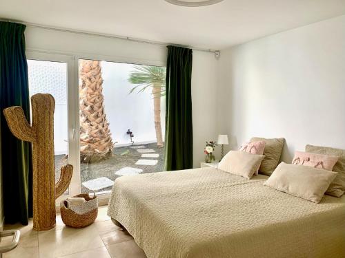 Villa del Mar Lanzarote - Luxury Beachhouse في أريثيفي: غرفة نوم بسرير ونافذة كبيرة فيها صبار