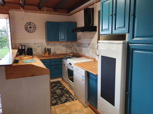 eine Küche mit blauen Schränken und einem weißen Kühlschrank in der Unterkunft Gîte du Grand Cher in Les Rousses