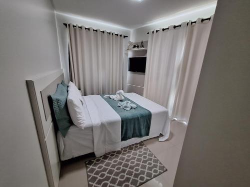 ein kleines weißes Schlafzimmer mit einem Bett und Vorhängen in der Unterkunft Cobertura Ap praia de Bombas in Bombinhas