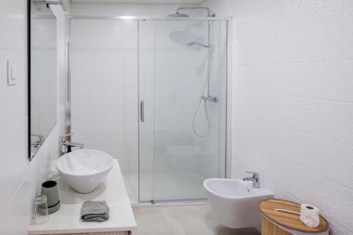 a white bathroom with a sink and a shower at Taste Tavira (by Annick) fully equipped apartment, tastefully decorated, perfect location and free parkingric center of the city of Tavira. in Tavira