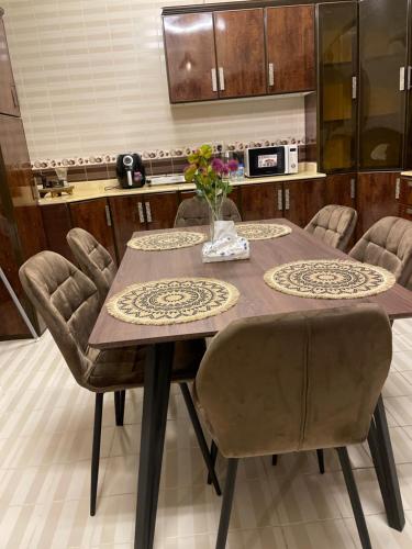 a kitchen with a table and chairs with flowers on it at شقة فندقية غرفتين نوم وغرفة معيشة ومدخل خاص وباركنج سيارة in Riyadh Al Khabra