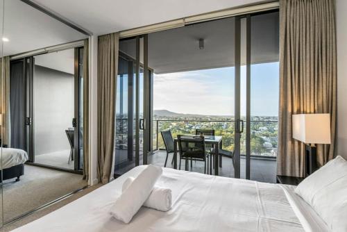 a bedroom with a bed and a balcony with a table at Stunning cityview 1BR Apt, 1 min to train in Brisbane