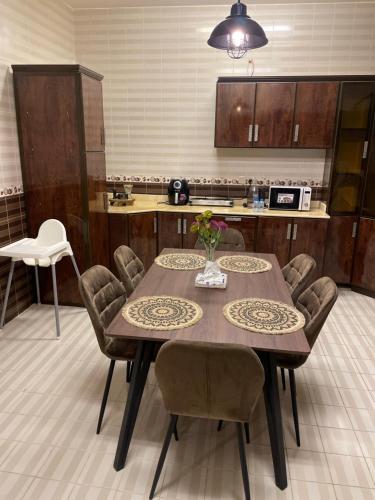 a kitchen with a wooden table with chairs and a tableasteryasteryasteryasteryastery at شقة فندقية غرفتين نوم وغرفة معيشة ومدخل خاص وباركنج سيارة in Riyadh Al Khabra