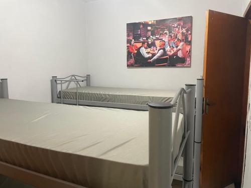 a bedroom with two beds and a painting on the wall at Escondidinho Bar, hostel e casa de festas in Rio de Janeiro
