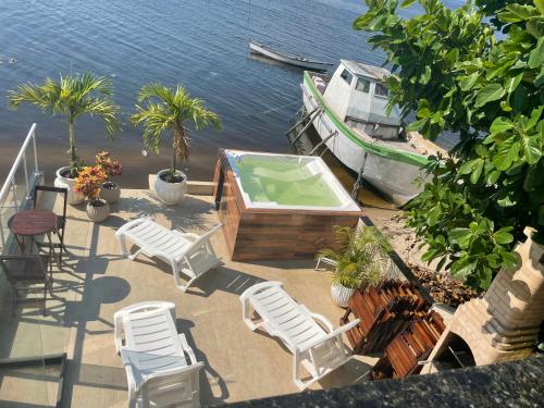a deck with chairs and a swimming pool and a boat at Escondidinho Bar, hostel e casa de festas in Rio de Janeiro