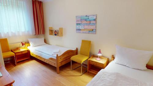 グレーミッツにあるGilde-Residenz App. 1のベッド2台と椅子が備わる小さな客室です。