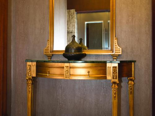a mirror and a table with a vase on it at The Way Hotel in Istanbul