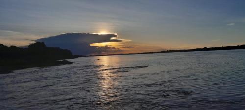 a sunset over a river with the sun hiding behind a cloud at Chalé Brisas do Rio in Petrolina