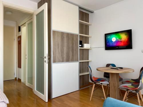 Cozy Apartment SOFI in Belville في Novi Beograd: غرفة مع طاولة وكراسي وتلفزيون