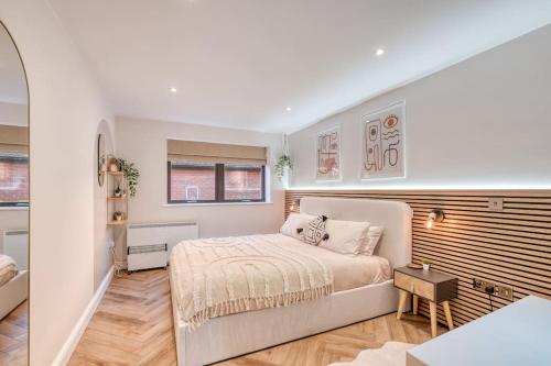 a white bedroom with a bed and a table at Stylish and modern city centre apartment with easy parking in Worcester