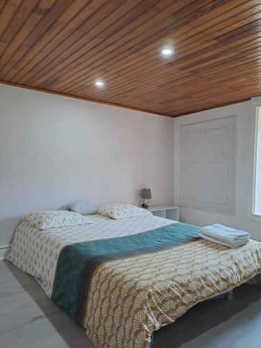 a bedroom with a large bed with a wooden ceiling at A Mammulejiu in Thiers