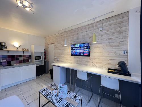 Il comprend une cuisine avec un bureau et une télévision sur un mur en briques. dans l'établissement Le Worker 1, à Calais