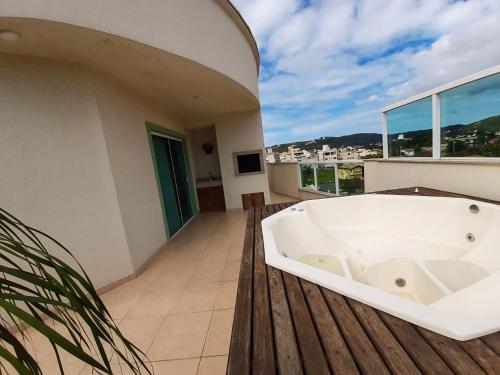 eine Badewanne auf einer Terrasse mit einem Balkon in der Unterkunft Cobertura Ap praia de Bombas in Bombinhas