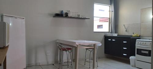 uma cozinha com uma mesa e dois bancos em kitnet Marilia 2 em Marília