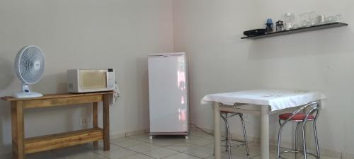 uma cozinha com um frigorífico, uma mesa e um micro-ondas em kitnet Marilia 2 em Marília