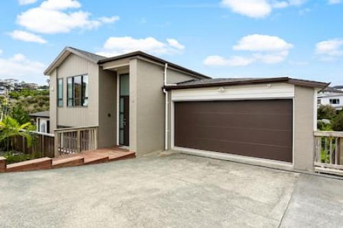 a house with a garage in front of it at Grand Retreat with spa pool and parking in Auckland
