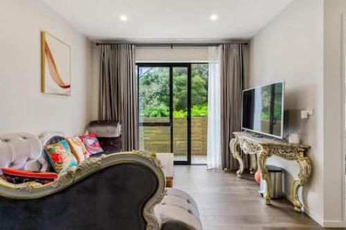 a living room with a couch and a television at Grand Retreat with spa pool and parking in Auckland