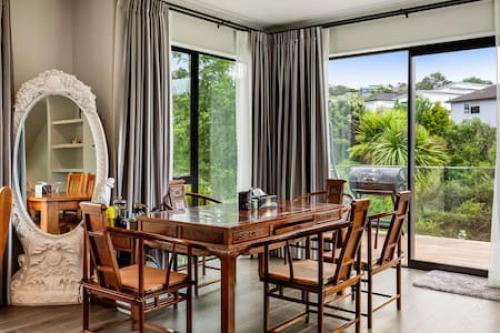 a dining room with a wooden table and chairs at Grand Retreat with spa pool and parking in Auckland